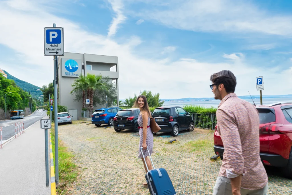 Una coppia cammina con una valigia verso l'Hotel Miramare vicino al mare.