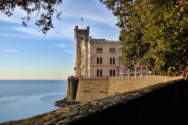 Castello affacciato sul mare con vista su un cielo limpido e alberi circostanti.